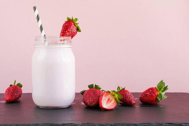 Strawberry milkshake with berry in mason jar on pink. Close up. Summer drink. - Photo, image
