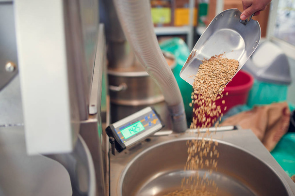 Photo of scoop with fresh coffee beans, industrial scales - 写真・画像