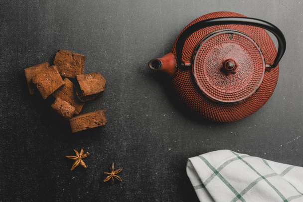 Japan iron teapot and chocolate marshmallows on dark background. Top view with space. - Фото, зображення