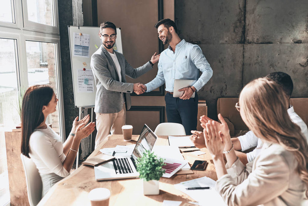 business people clapping and smiling while partners shaking hands in office - Photo, Image