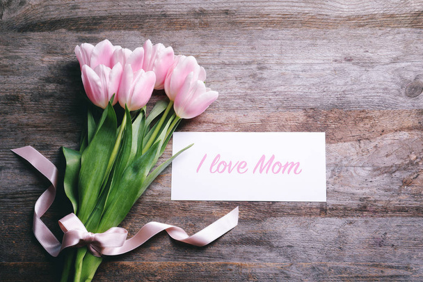 Komposition mit Grußkarte und Tulpen zum Muttertag auf Holzgrund, Draufsicht - Foto, Bild