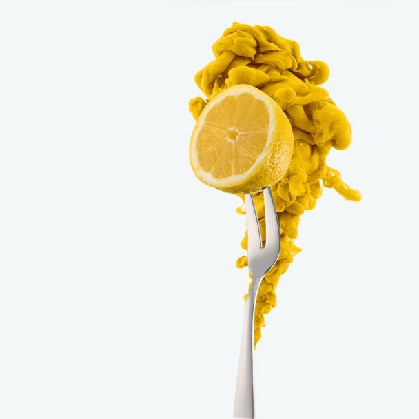 half of lemon on fork and yellow ink isolated on white - 写真・画像