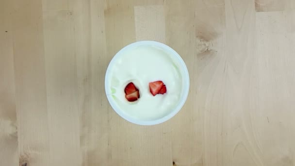 healthy strawberries falling down on white yogurt in slow motion on wood table, concept of healthy food nutrition - Video
