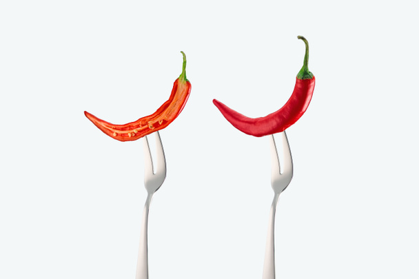 paloiteltu ja kokonainen punainen chili-paprika valkoisella eristetyissä haarukoissa
 - Valokuva, kuva