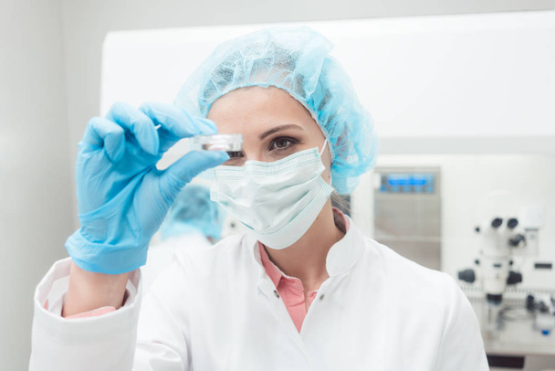 Nainen tiedemies esittelee uusinta biotekniikkakoettaan laboratoriossa
 - Valokuva, kuva