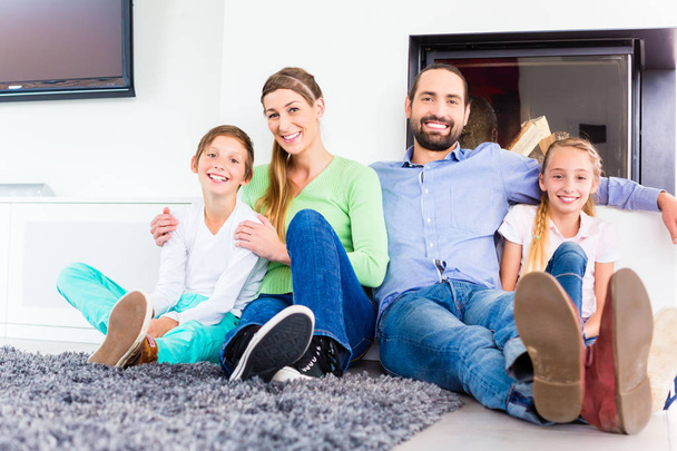Family sitting at living room floor fireplace - Foto, Imagem