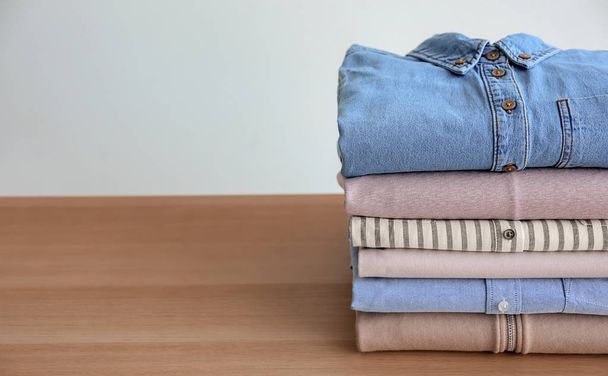 Stack of clothes on table against light background - Foto, afbeelding