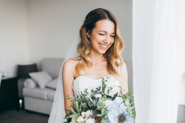 young  beautiful  bride holding flowers  indoors - Фото, изображение