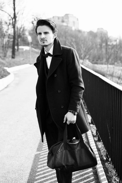Black and white photo of stylish handsome young man posing on the street - Foto, Imagem