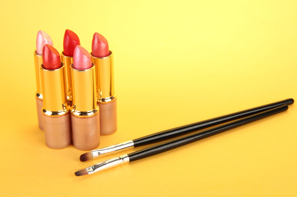 Lipsticks and brushes on yellow background - Photo, image