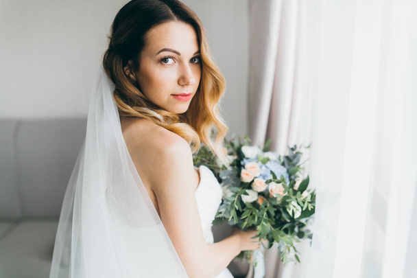 young  beautiful  bride holding flowers  indoors - Foto, imagen