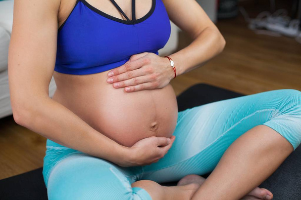 Una joven mujer embarazada hermosa se dedica al yoga para las mujeres embarazadas. Deportes para mujeres embarazadas. Una joven embarazada. Salud. Yoga embarazada. Maternidad
. - Foto, imagen