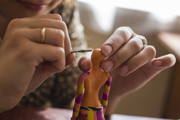 Enseñando a los estudiantes el arte de modelar. Escultura de plastilina. Una chica moldea una muñeca con sus manos
. - Foto, imagen