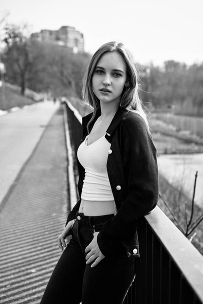 Black and white photo of pretty young woman in casual clothes posing on the street                  - Zdjęcie, obraz