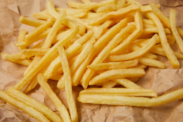 primo piano di deliziose patatine fritte versate su carta spiegazzata
 - Foto, immagini