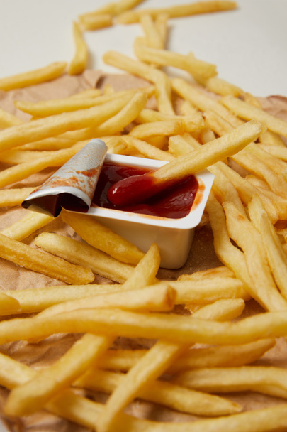 batatas fritas em papel amassado com recipiente de ketchup
 - Foto, Imagem