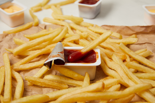 gros plan des frites sur papier froissé avec des contenants de sauces
 - Photo, image