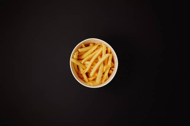 top view of delicious french fries in bowl isolated on black - Photo, Image