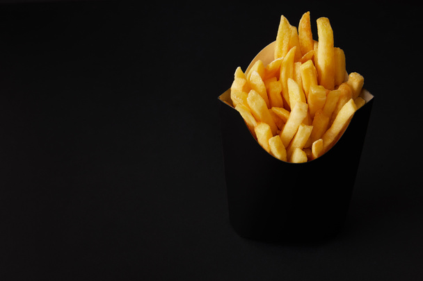 black box of tasty french fries isolated on black isolated on black - Foto, afbeelding