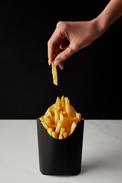 woman taking out french fry from box isolated on black - Фото, зображення