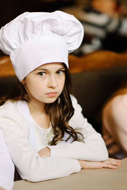 Cute girl in a white cap is a chef's chef - Fotó, kép