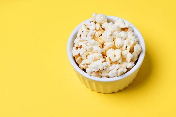 Fresh pop corn. Small white bowl. Bright yellow background - Foto, afbeelding