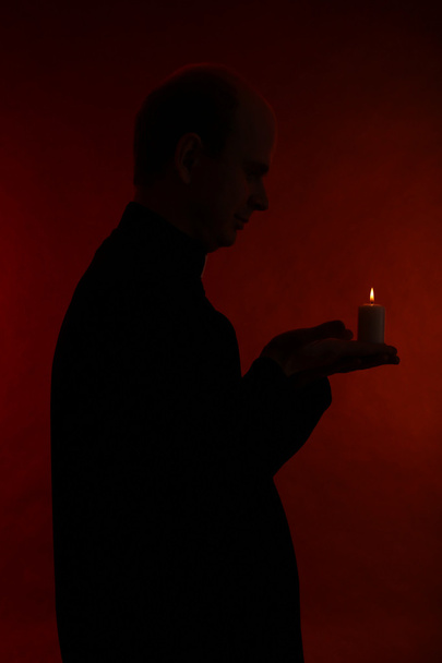 Portrait of young Pastor holding candle in his hand, isolated on black - Foto, imagen