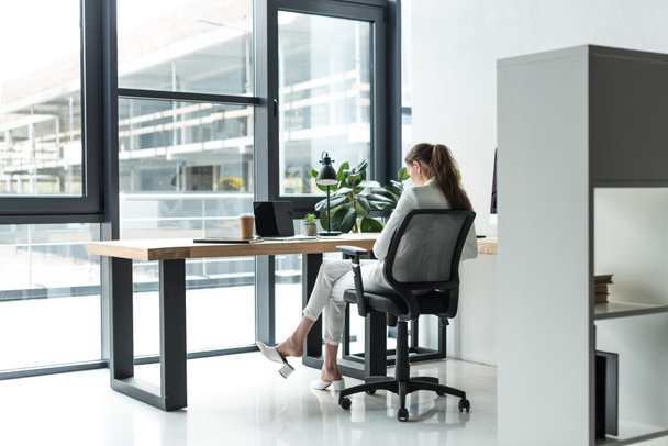 back view of businesswoman sitting at workplace in modern office - Foto, afbeelding