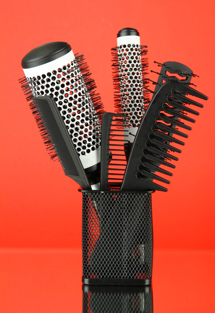 Iron basket with combs and round hair brushes, on color background - Foto, Bild
