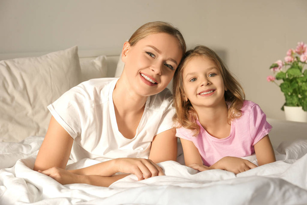 Happy mother and her daughter on bed in children room - Photo, image