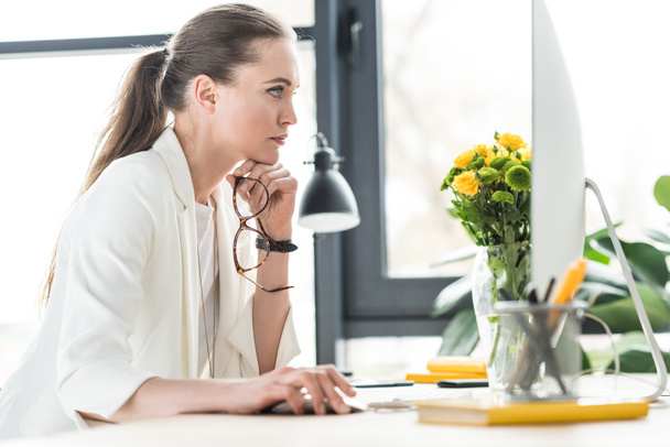 side view of focused businesswoman looking at computer screen at workplace in office - Photo, Image