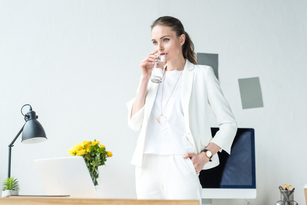 portrait of businesswoman drinking water from glass at workplace in office - Fotó, kép