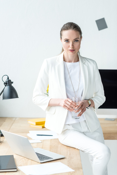 Porträt einer Geschäftsfrau mit einem Glas Wasser am Arbeitsplatz mit Laptop im Büro - Foto, Bild