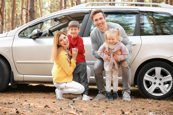 Jong (echt) paar met hun kleine kinderen in de buurt van auto in de pine forest - Foto, afbeelding