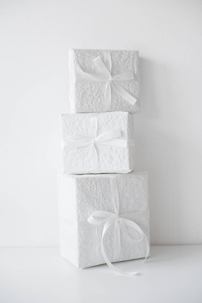 Trzy pakiety pola białe prezent z wstążkami na stole  - Zdjęcie, obraz