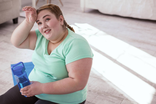Plump young woman resting after workout on the yoga mat - Photo, Image