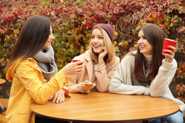 Beautiful smiling women with coffee in outdoor cafe - Foto, imagen