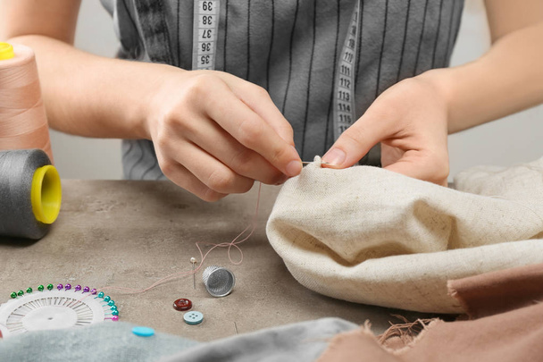 Seamstress sewing at table in workshop - Фото, зображення