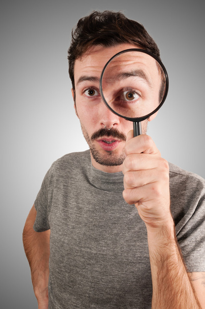 man looking through a magnifying lens - Фото, изображение