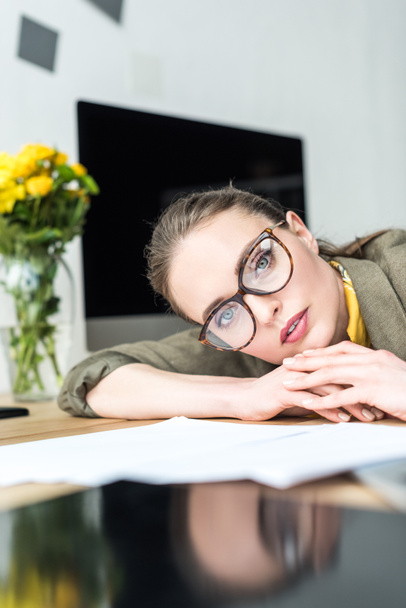 beautiful businesswoman in eyeglasses looking at camera at workplace  - Foto, Imagem