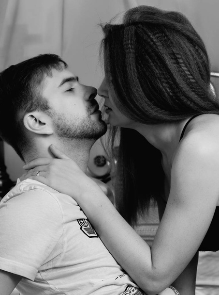 Young beautiful loving couple is embracing on a bed. ntimate image of sensual couple foreplay, kissing passionately. black and white - Foto, imagen