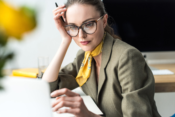 ελκυστικό μέσα ενηλίκων επιχειρηματίας σε γυαλιά, κάθεται στο χώρο εργασίας - Φωτογραφία, εικόνα