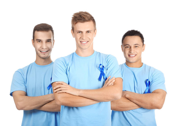 Young men in t-shirts with blue ribbons on white background. Prostate cancer awareness concept - Foto, afbeelding