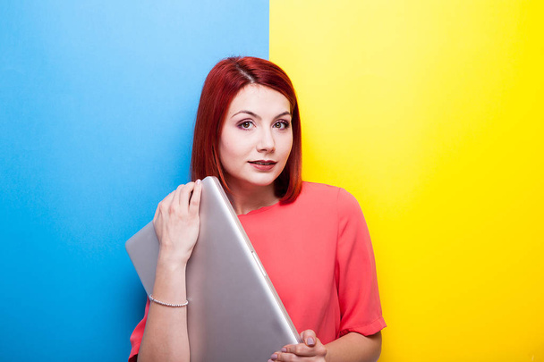 Mosolygós vörös hajú nő, a kezében egy szürke premium laptop - Fotó, kép