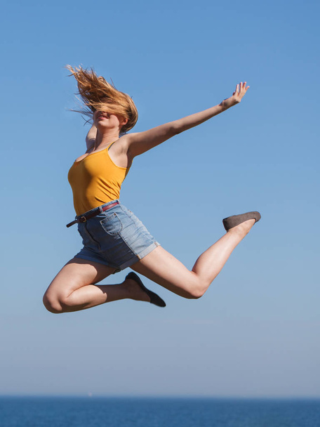 Carefree woman jumping by sea ocean water. - Foto, Imagen
