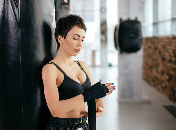 beautiful female with short black hair putting on straps while work out - Foto, afbeelding