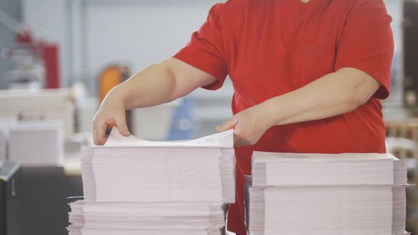 Mãos femininas classificam as pilhas de jornais na tipografia
 - Foto, Imagem