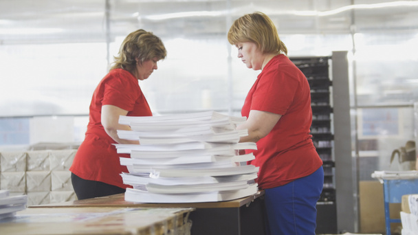 Женщины-рабочие сортируют бумажные стопки в типографии
 - Фото, изображение