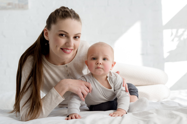 smiling mother with little baby boy lying on bed - Foto, imagen