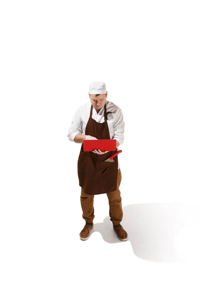 Serious butcher posing with a laptop isolated on white background - Foto, Imagem